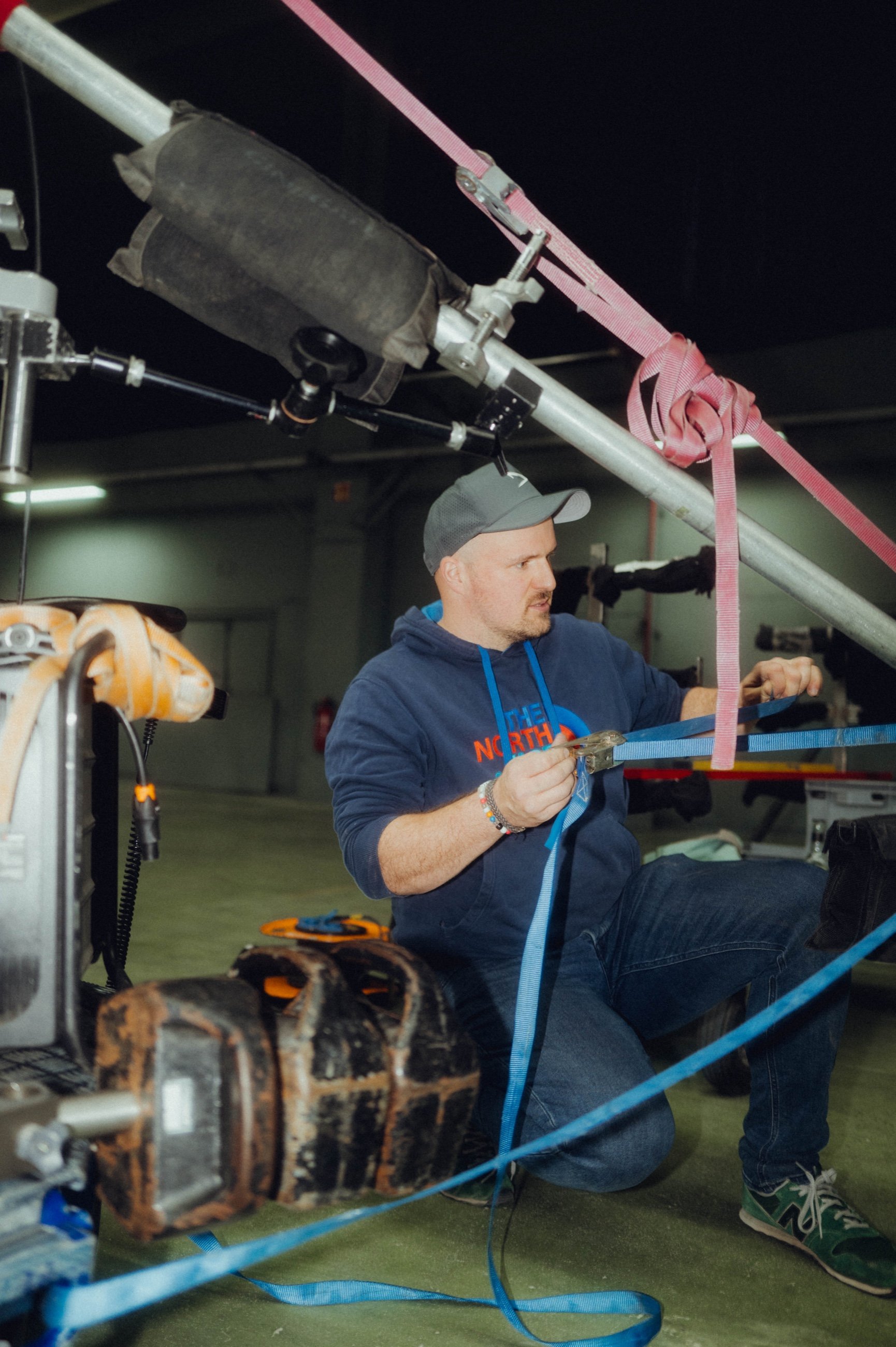 Crewmitglied kniet am Boden und zurrt Kabel und Rigging fest