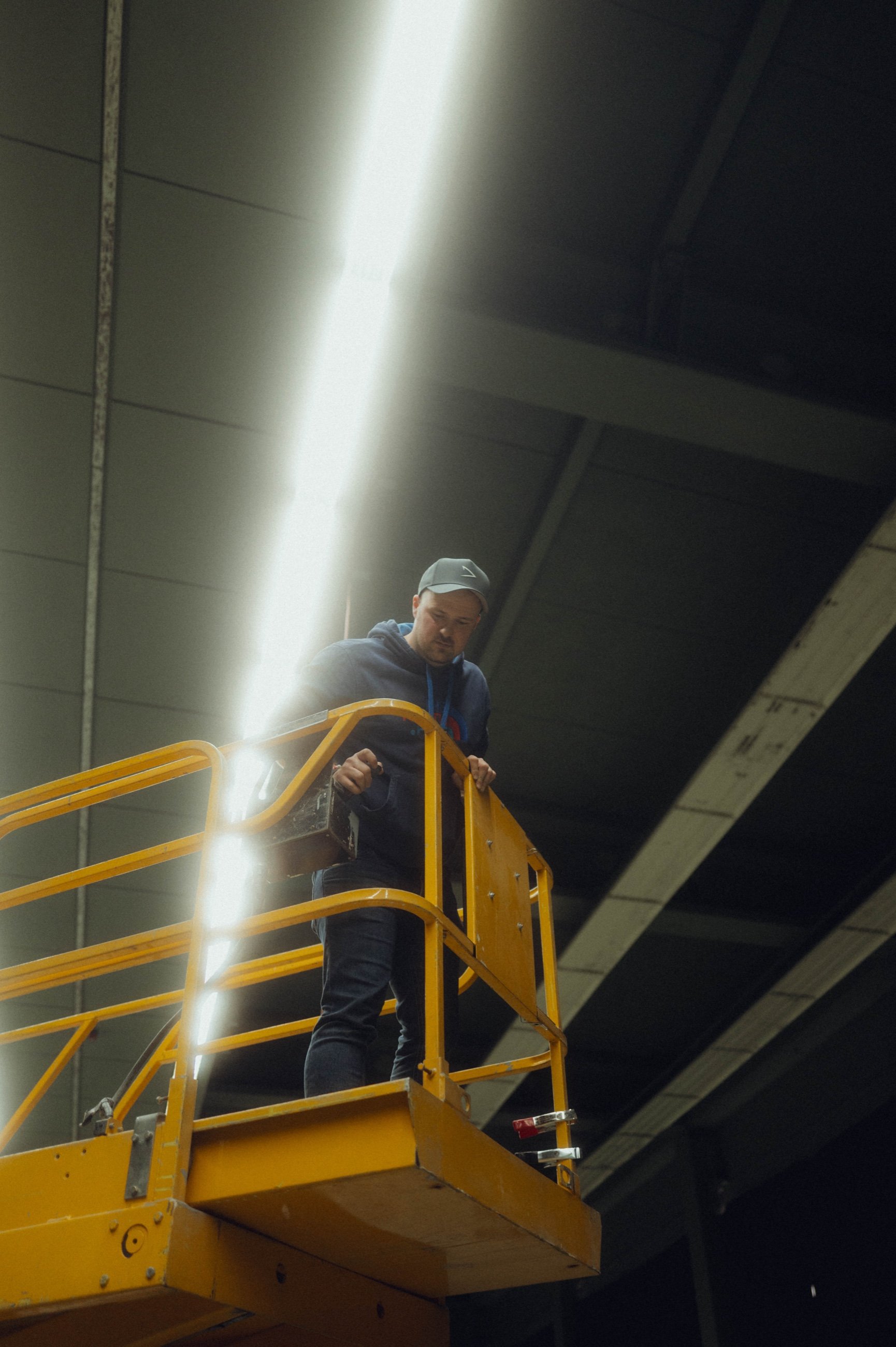 Person auf einer gelben Hebebühne in einem Lichtstrahl