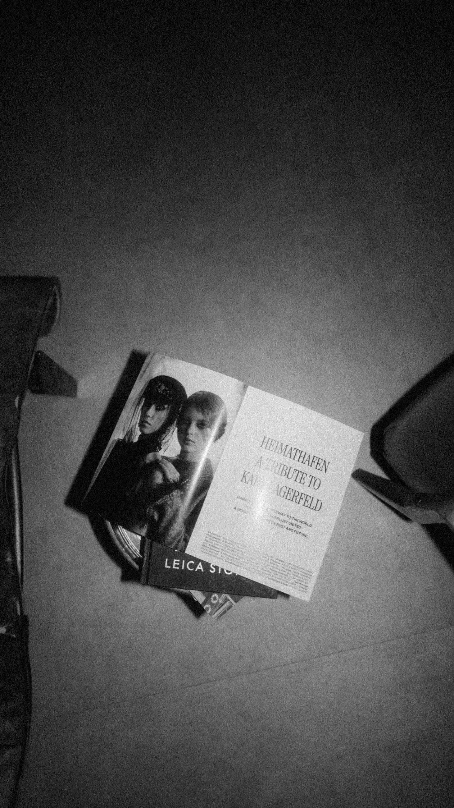 Aufgeschlagenes Heft auf dem Boden, daneben ein Buch vom Leica Store