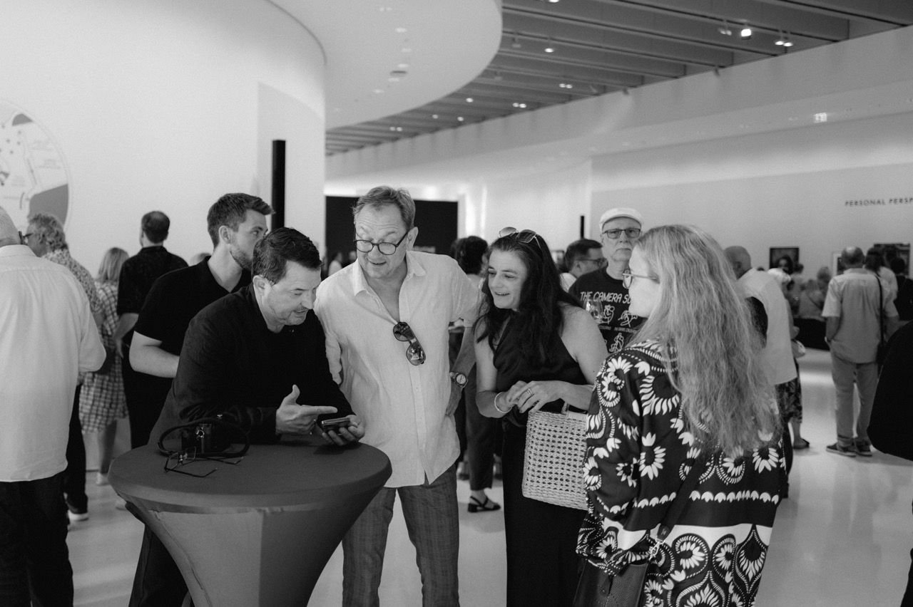 Small group at a bar table, one person showing something on a display