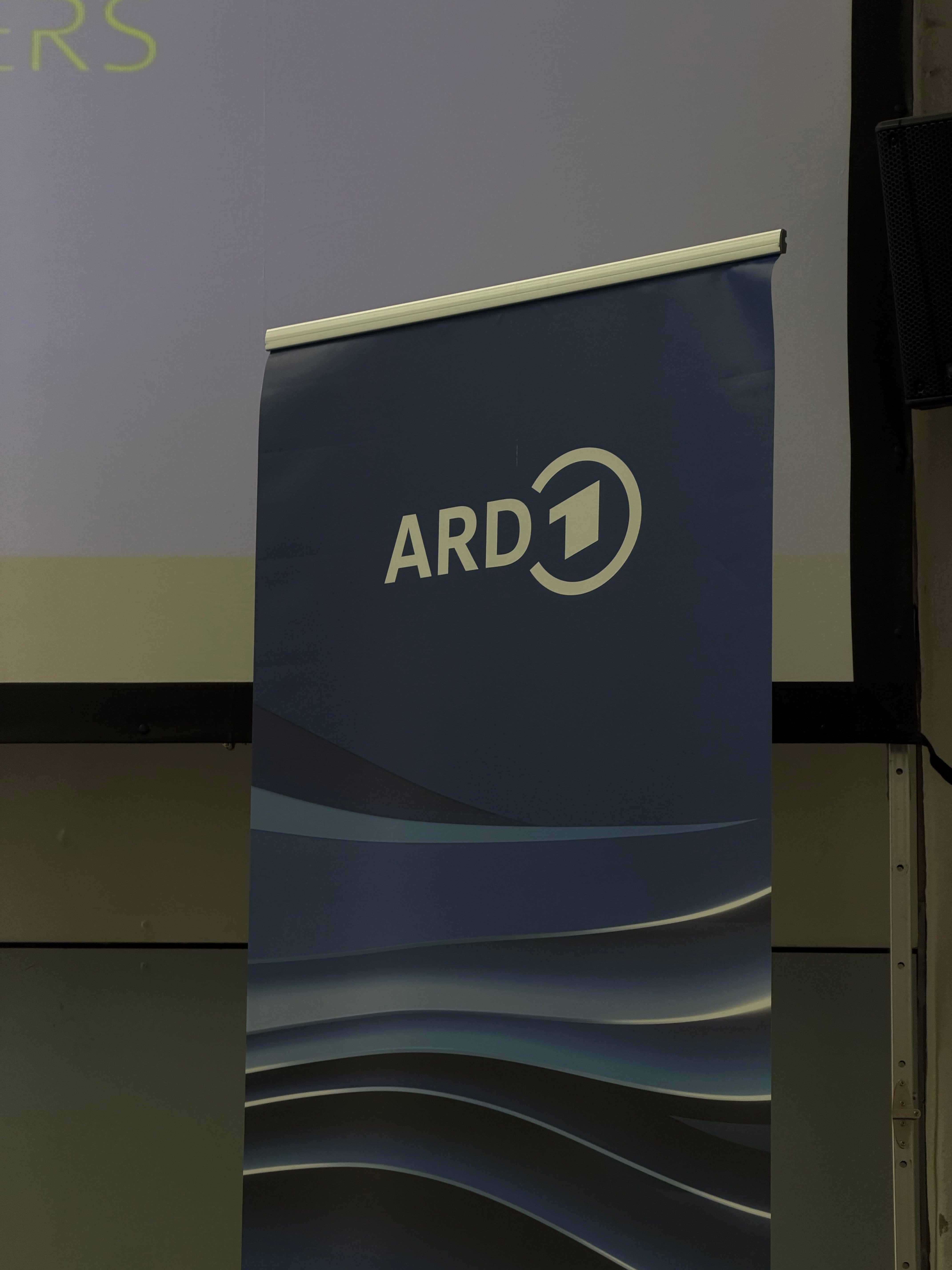 ARD-Banner in Blautönen vor der Leinwand