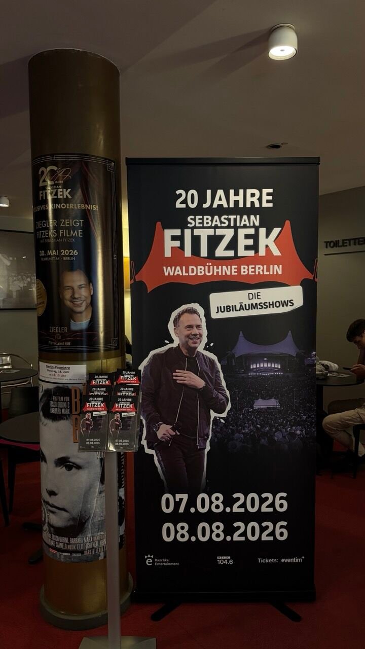 Rollup im Kinofoyer mit dem Schriftzug „20 Jahre Sebastian Fitzek, Waldbühne Berlin“ und den Terminen im August 2026