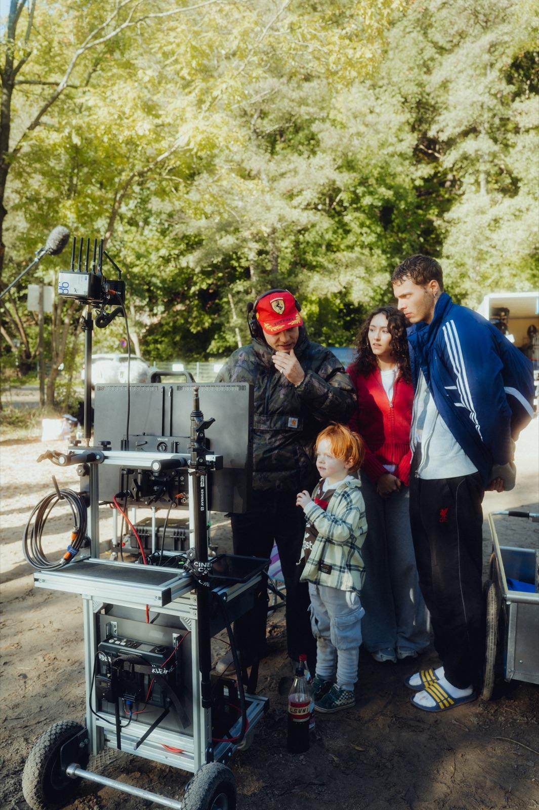Behind the Scenes: am Monitor-Wagen schauen Regie mit roter Cap, die Darsteller und der kleine Ronni gemeinsam aufs Playback