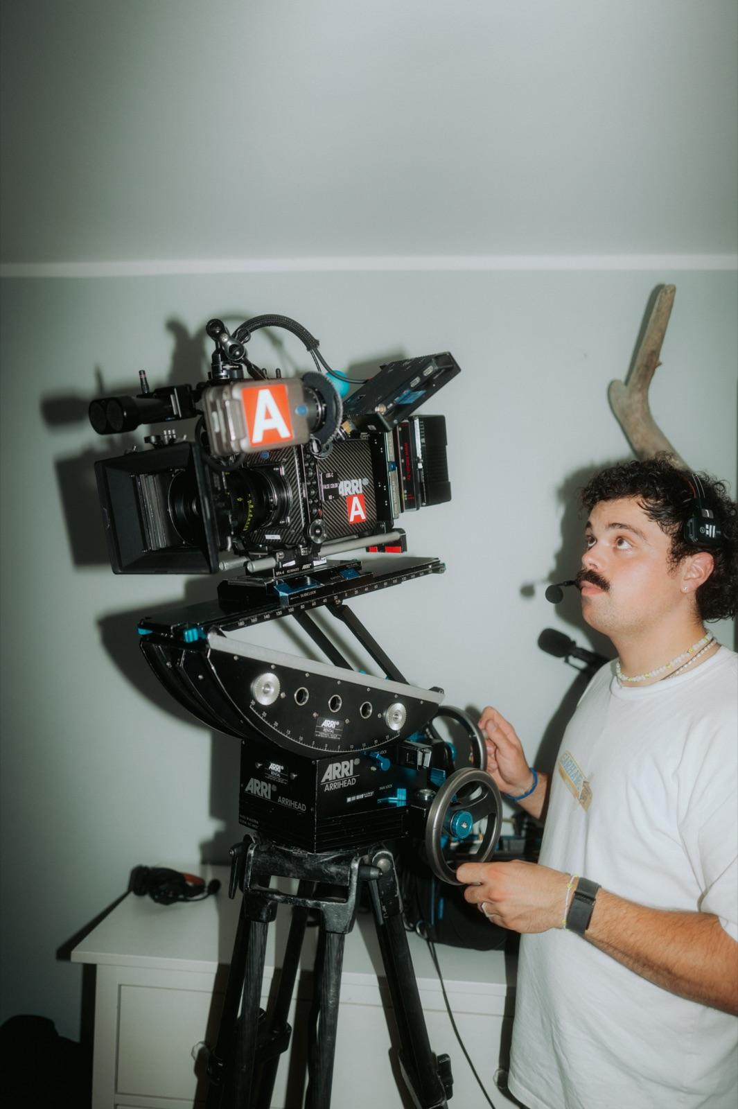 Behind the Scenes: der Kameramann am Getriebekopf der ARRI in einem Innenraum, konzentriert nach oben blickend