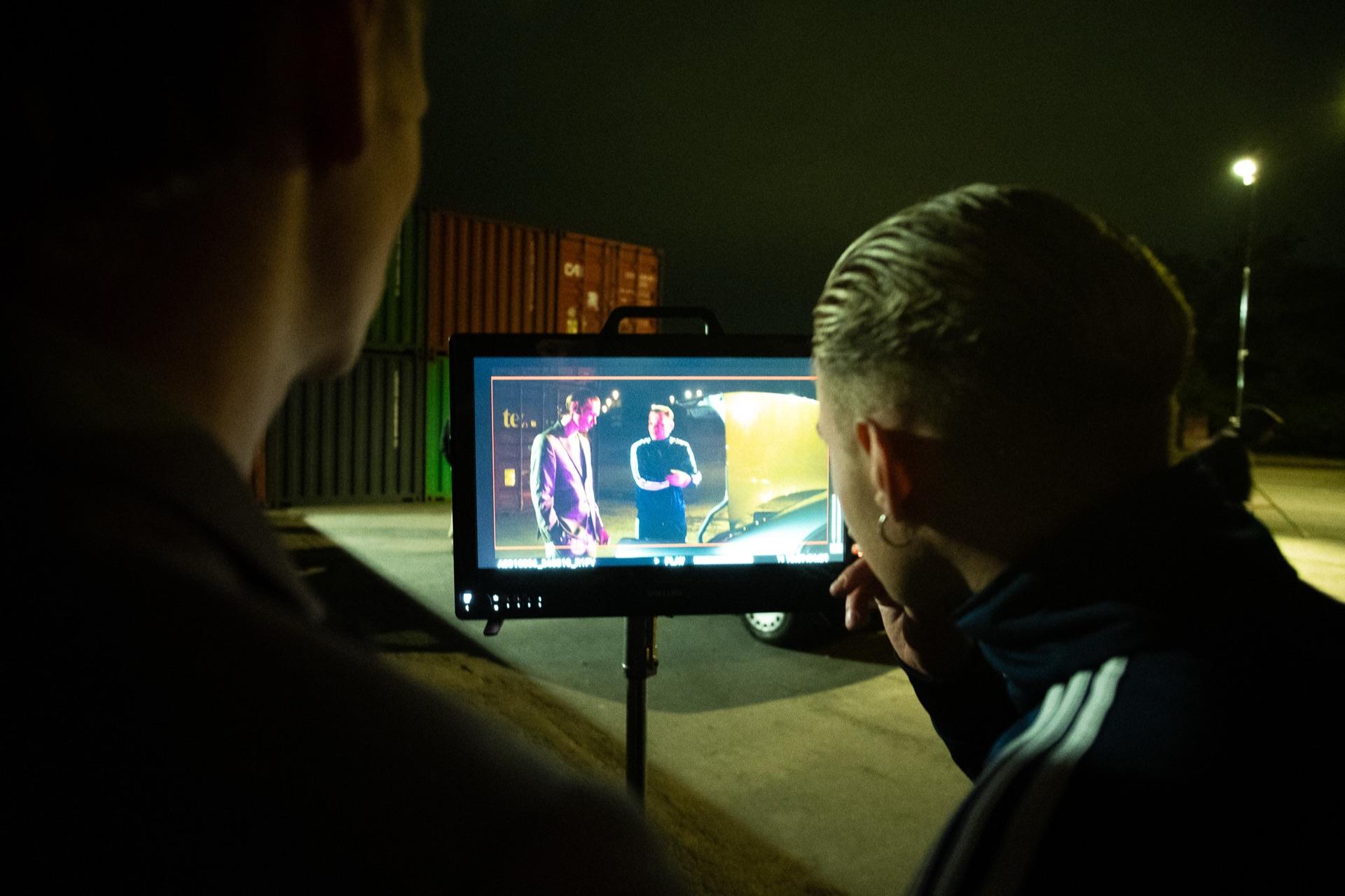 Behind the scenes: two crew members check the shot on the monitor, the two actors on the display