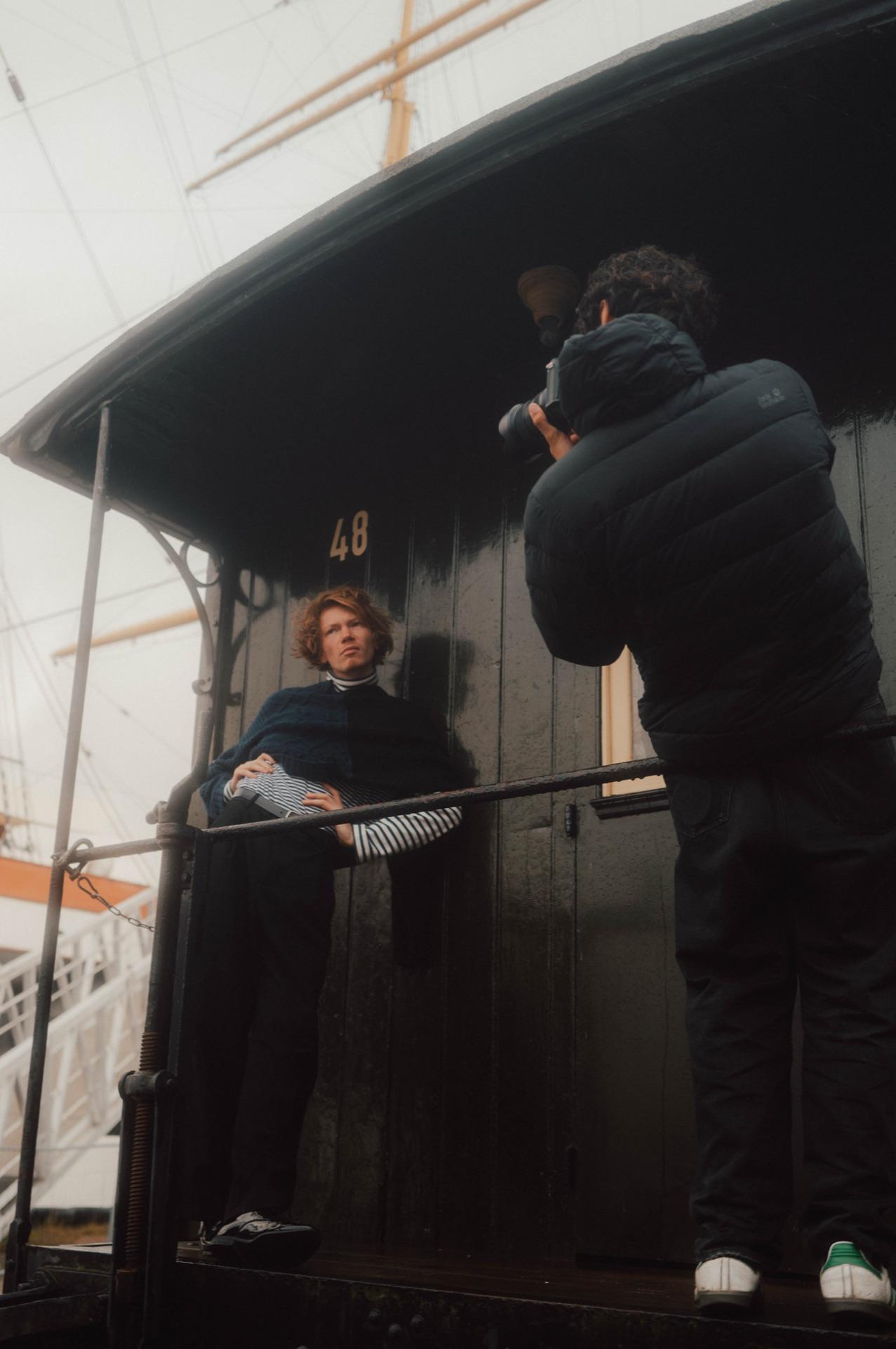 Behind the Scenes: Filip Schnack lehnt am grünen Schiffsrumpf, während der Fotograf ihn ablichtet