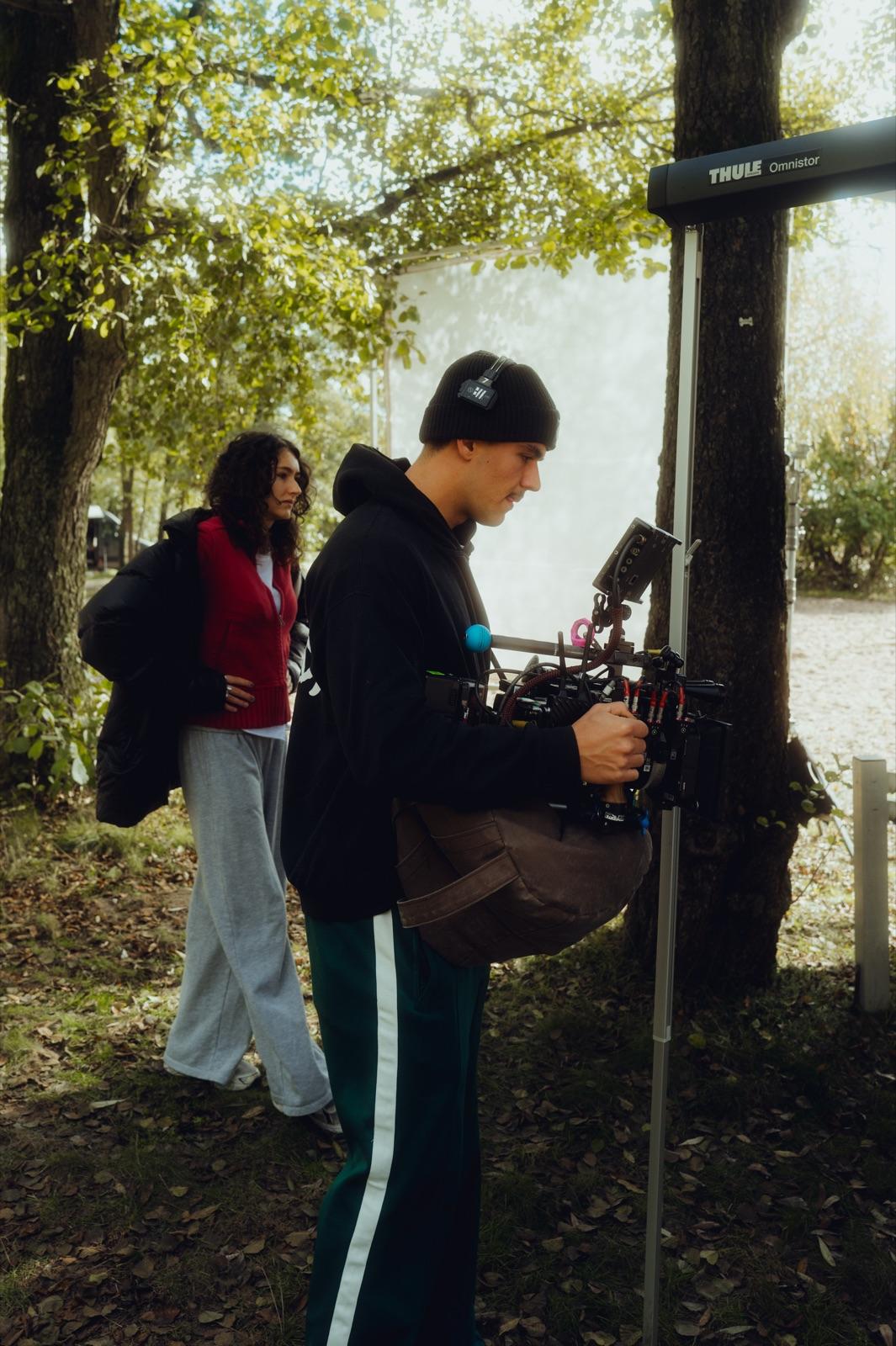 Behind the Scenes: ein Operator mit Mütze führt die Kamera am Gimbal, eine Darstellerin folgt im Hintergrund