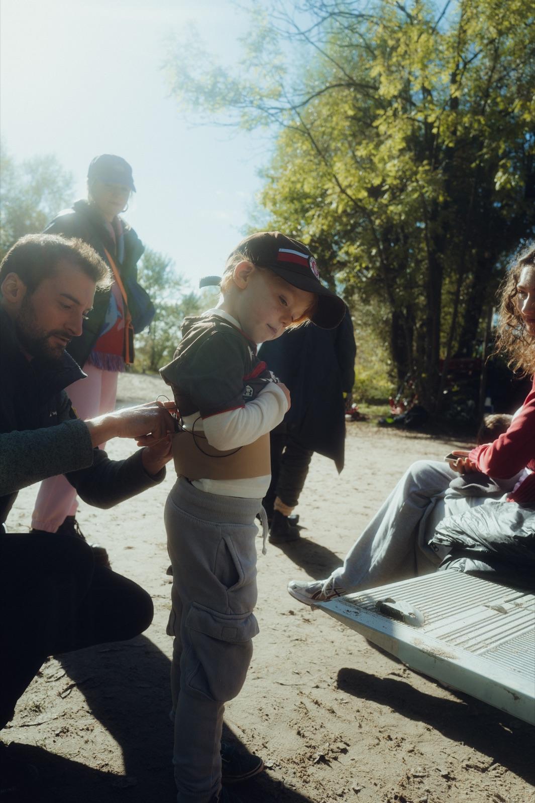 Behind the Scenes: ein Crew-Mitglied kniet im Sonnenlicht und richtet dem Kinderdarsteller das Kostüm