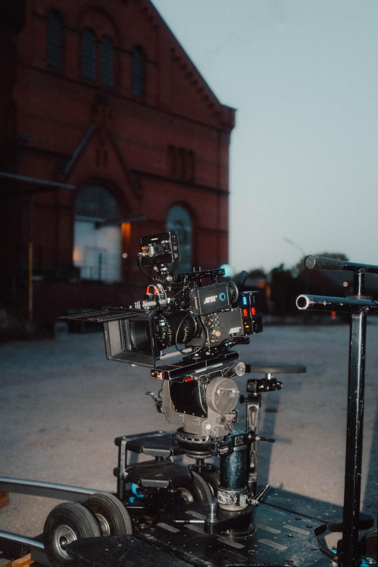 Die Filmkamera auf dem Dolly vor einem roten Backsteingebäude in der Abenddämmerung