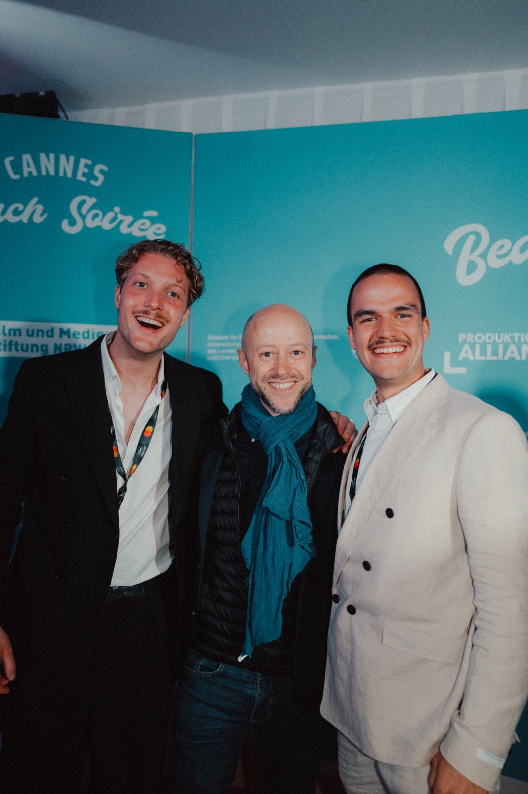 Jakob Hermann Haehner, Fabian Gasmia und Johannes Fielers beim Empfang vor einer Cannes-Fotowand