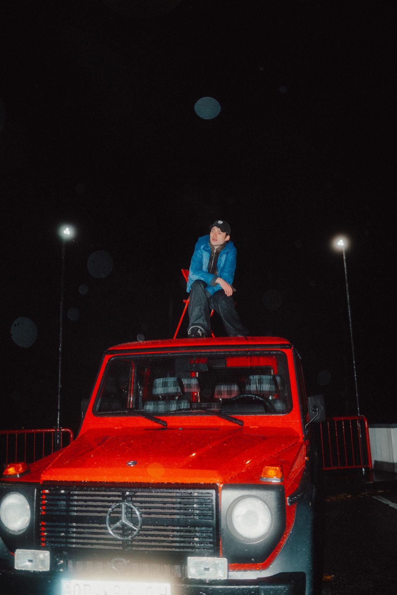 People around a red-lit pickup truck in the dark