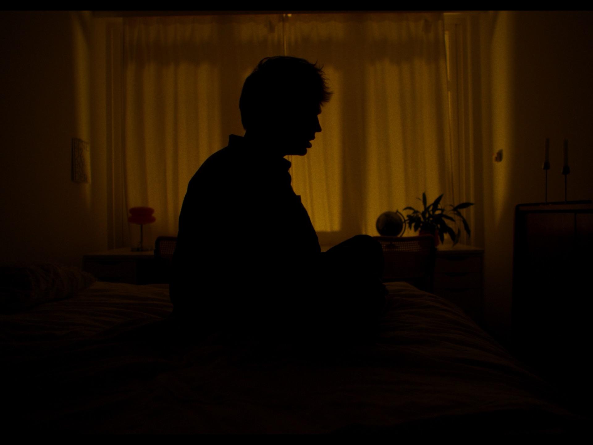 Jaschu als Silhouette vor einem warm leuchtenden Vorhang