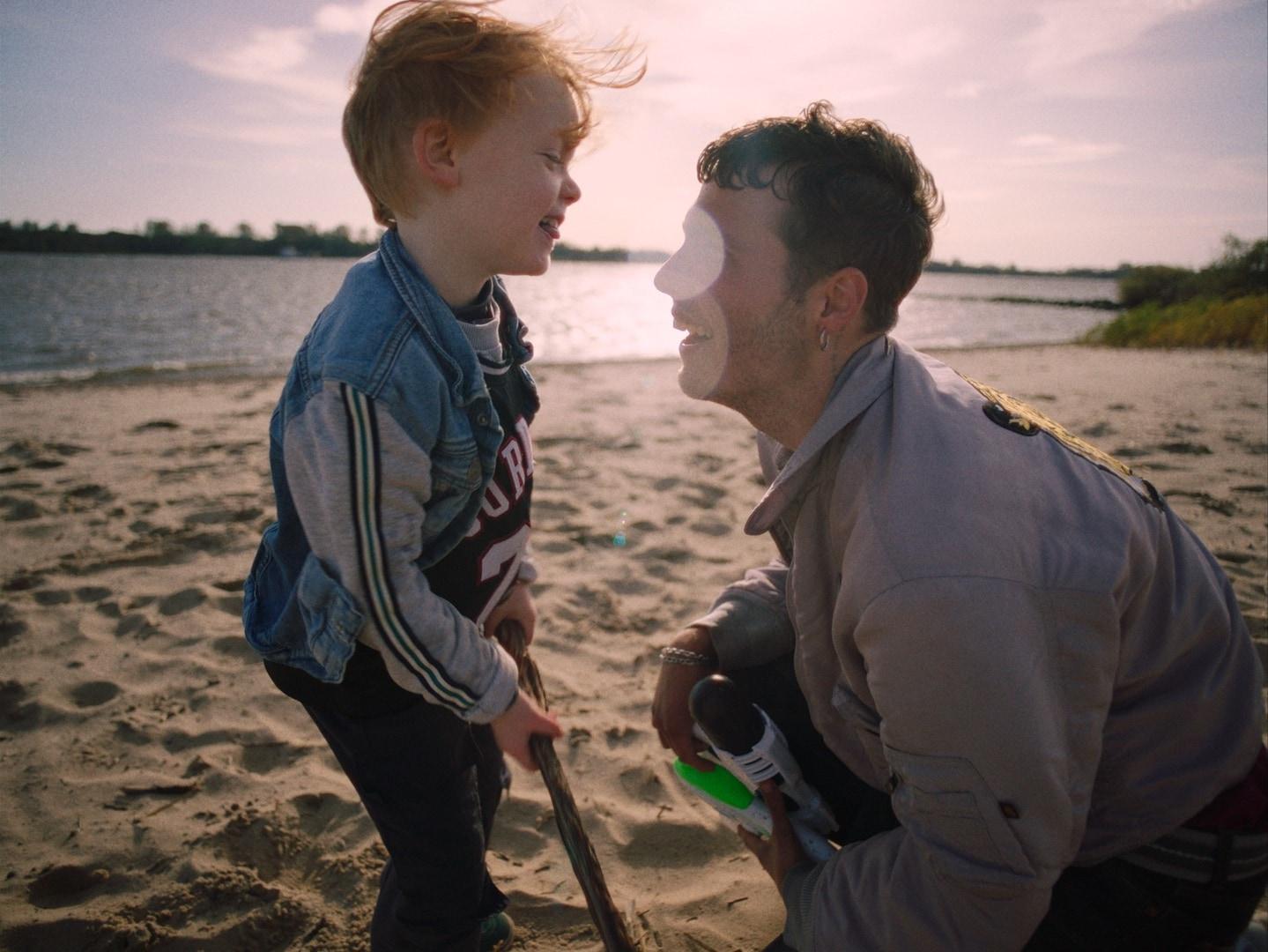 Leo und Ronni Stirn an Stirn am Strand, mit einer Wasserpistole, im Abendlicht