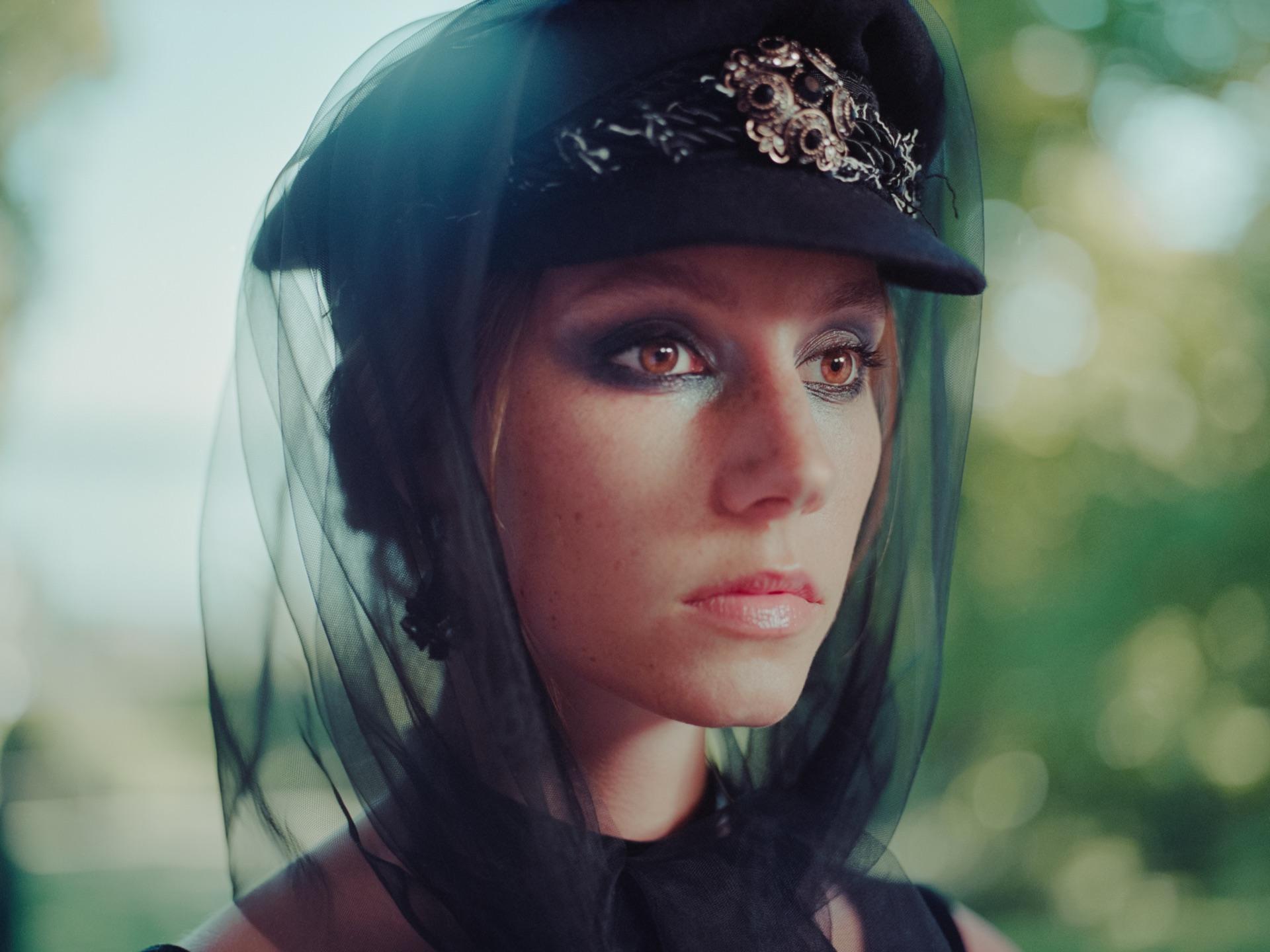 Close-up portrait of a model with a black veil and cap