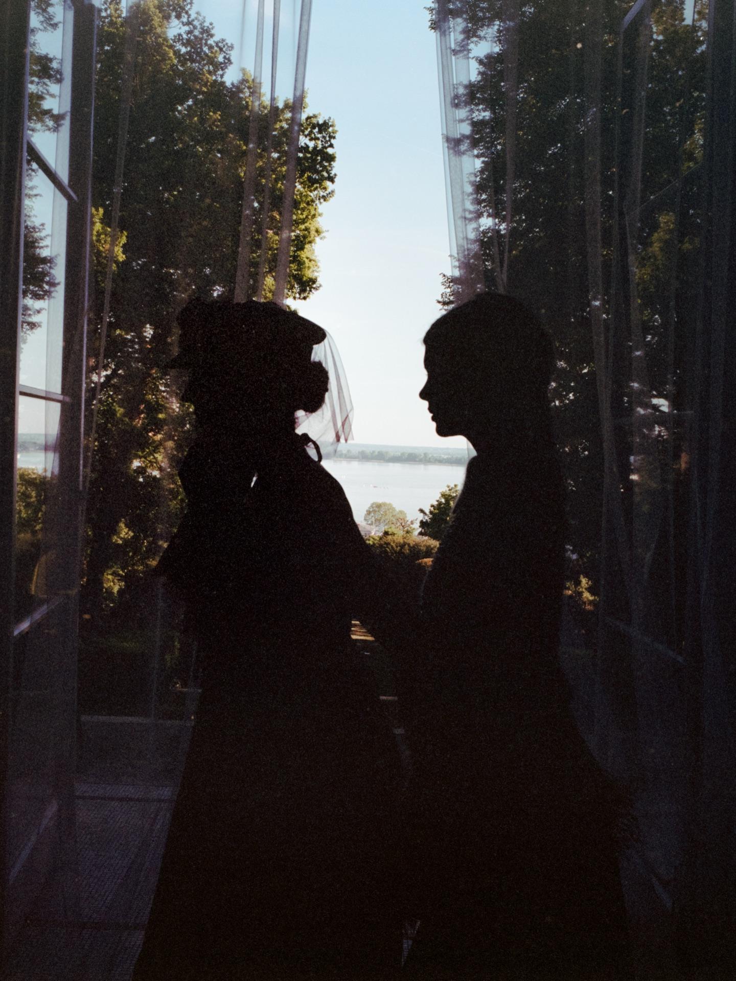Two models as silhouettes against a bright French door