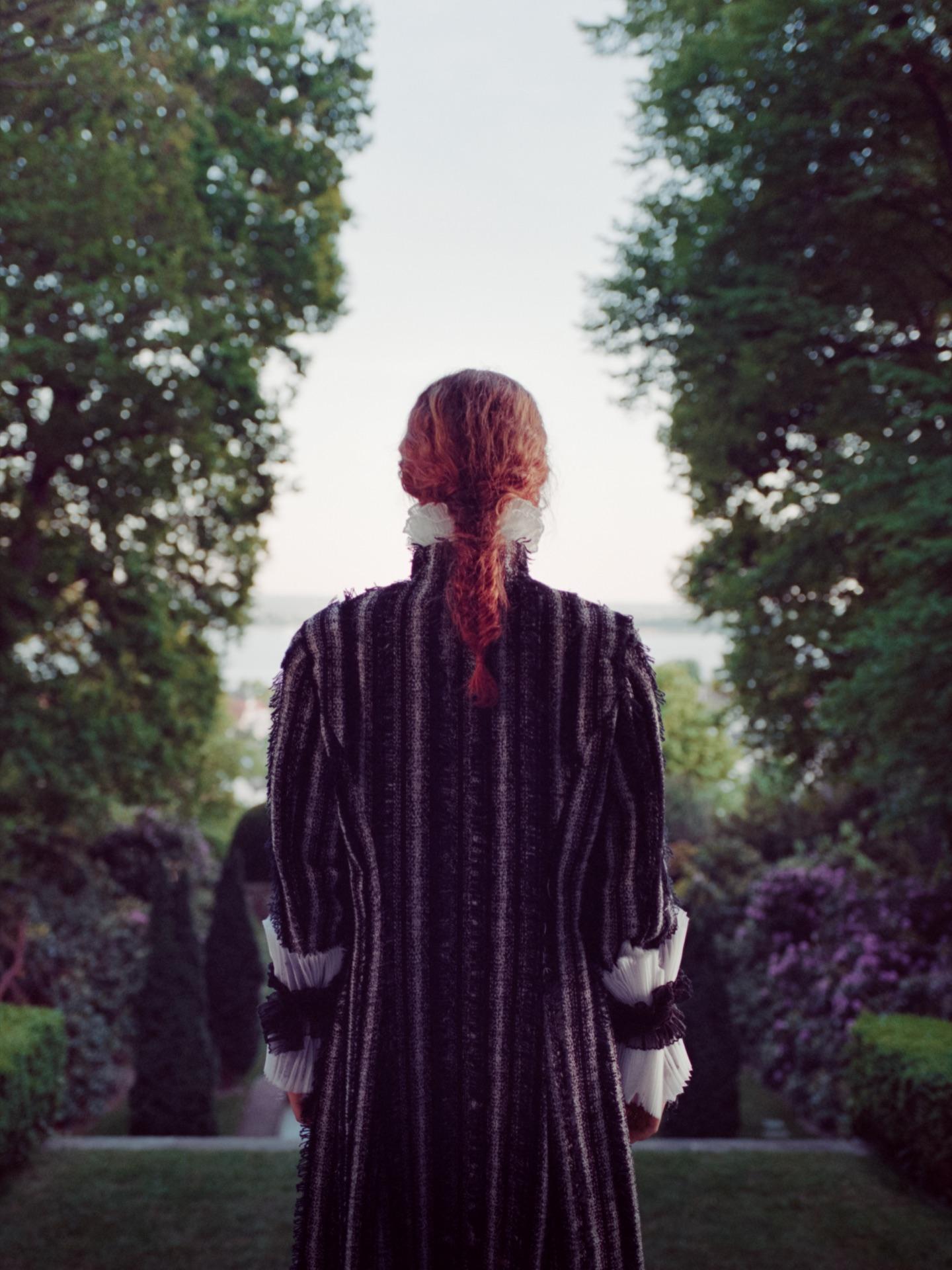Model from behind in a striped coat, looking into the park