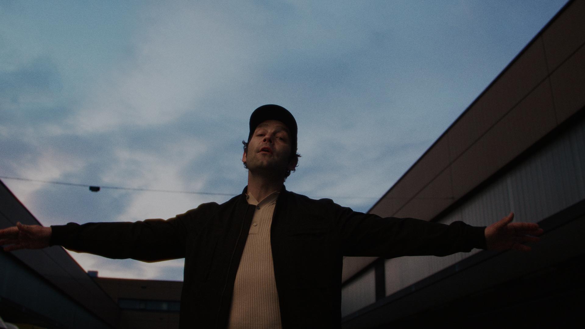Bosse with arms spread wide against the evening sky