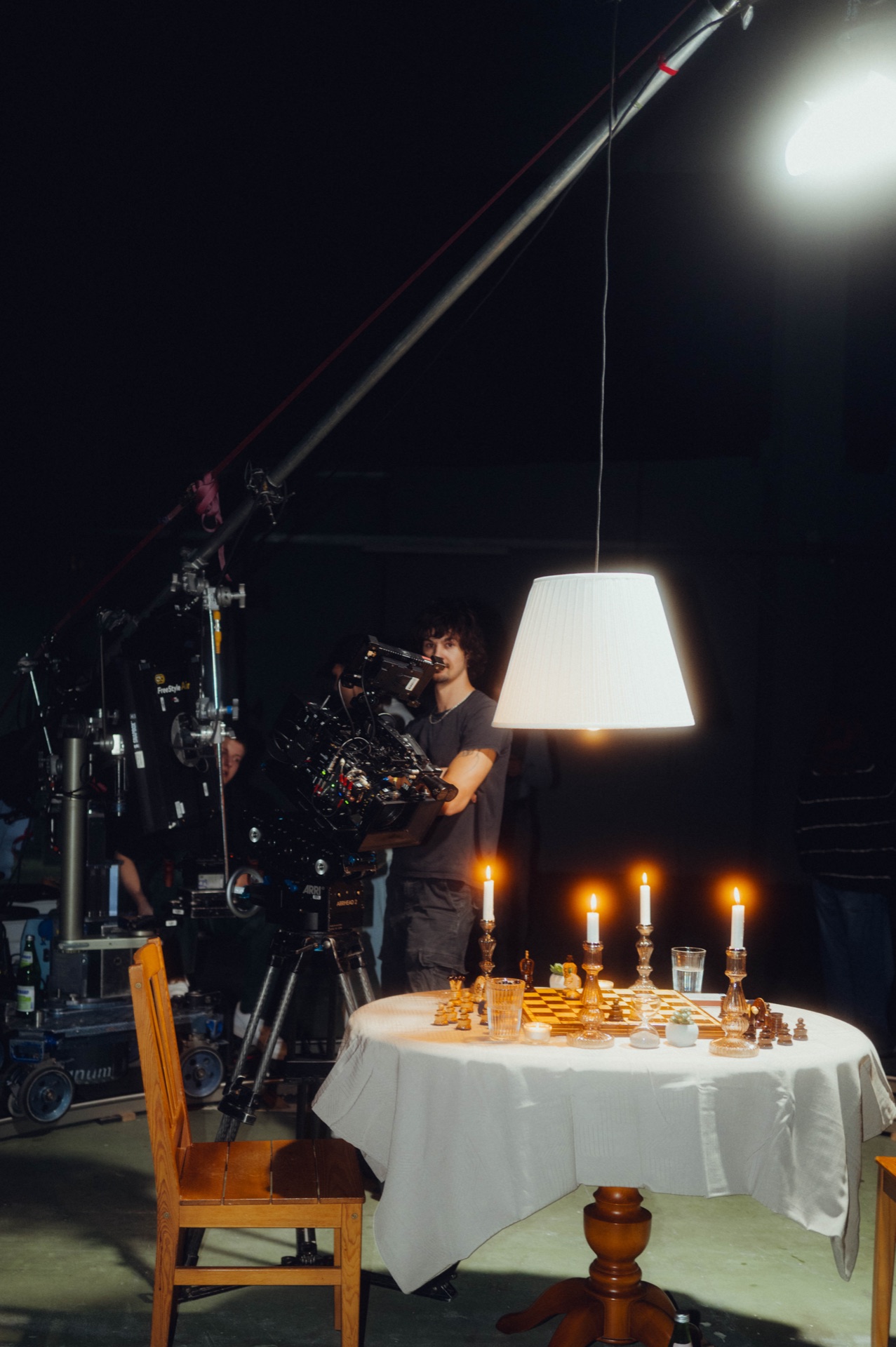Das Set: der gedeckte Tisch mit Schachbrett und Kerzen unter einer Hängelampe, Kamera davor